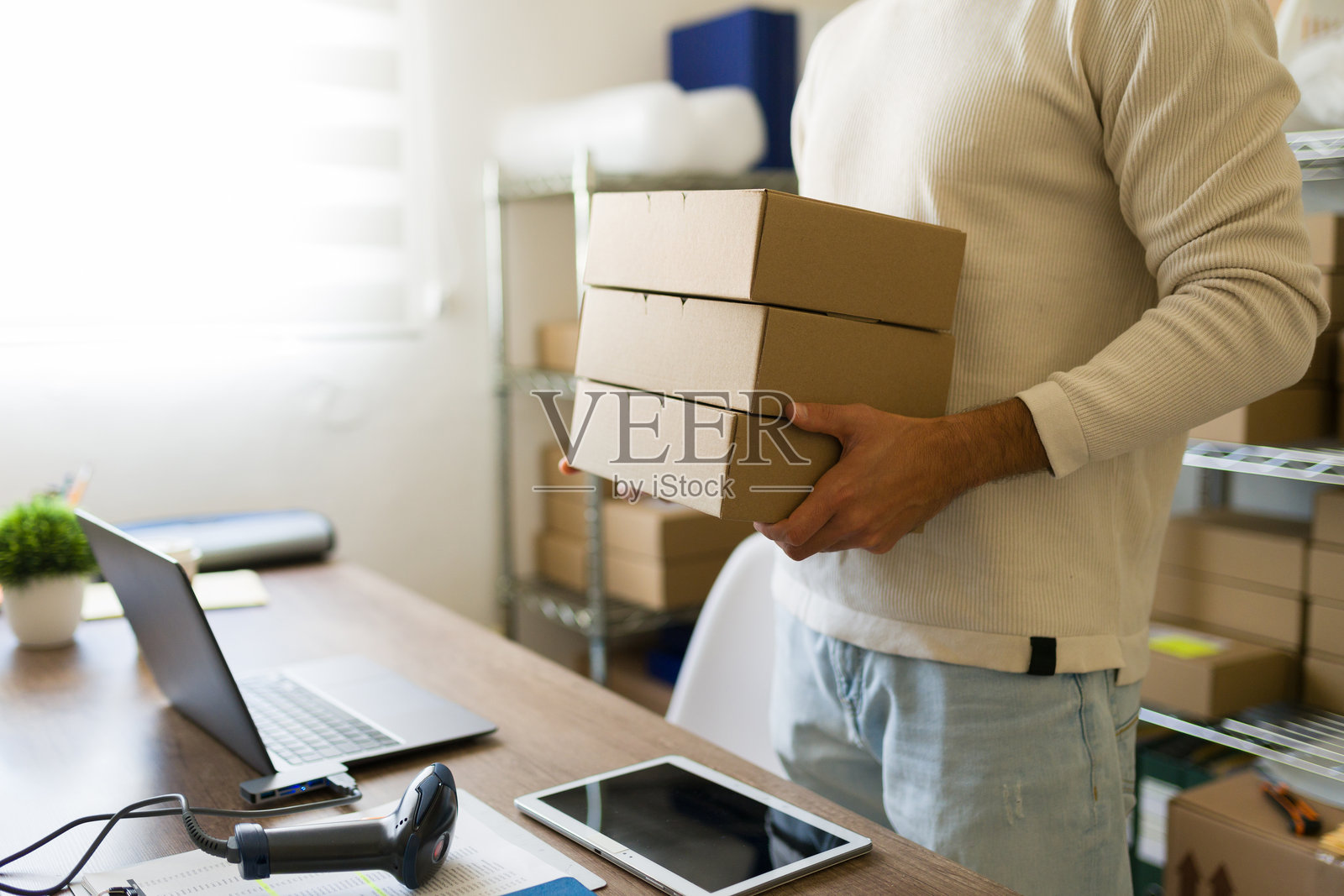 小企业主在仓库中整理电子商务订单并准备发货，手里提着纸箱的特写镜头照片摄影图片