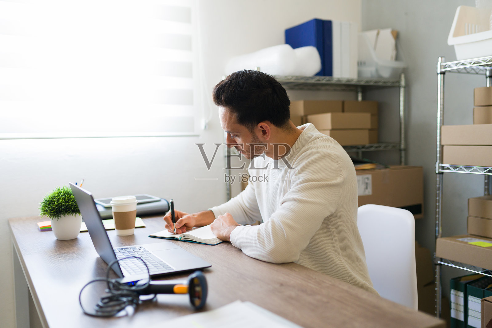 拉丁裔企业家在他的商店中记录在线订单并打包货物照片摄影图片