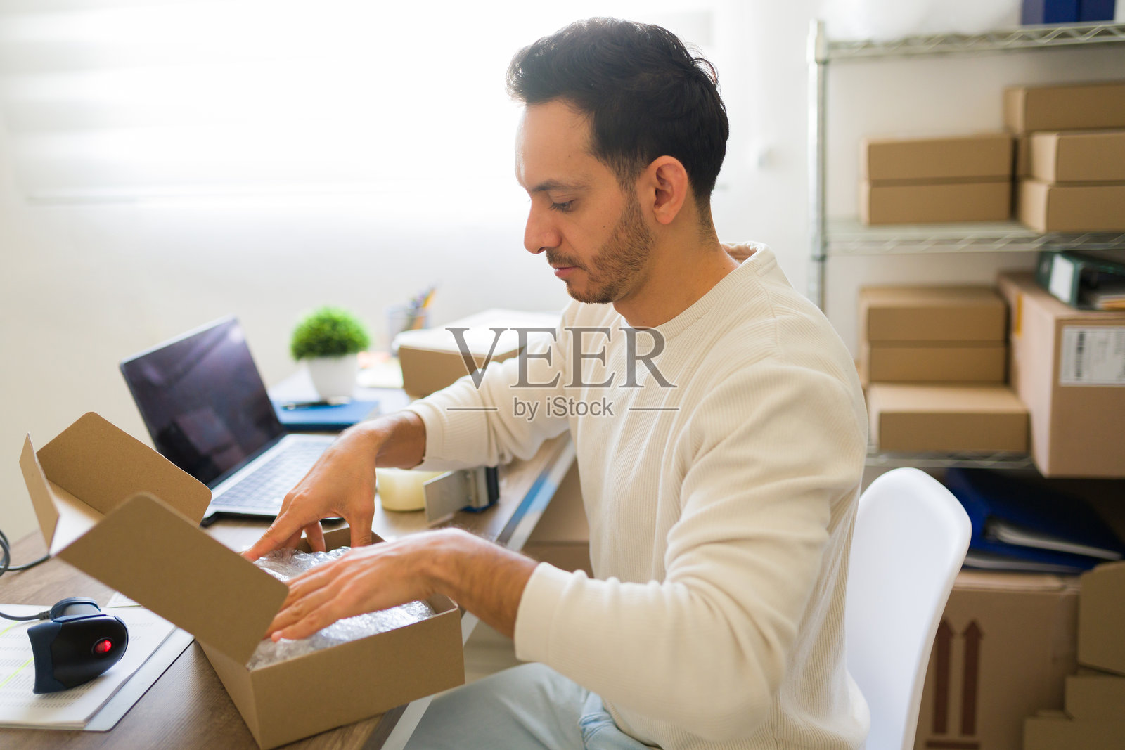 小企业主在家办公室仔细将产品打包进纸箱，准备发货订单。照片摄影图片