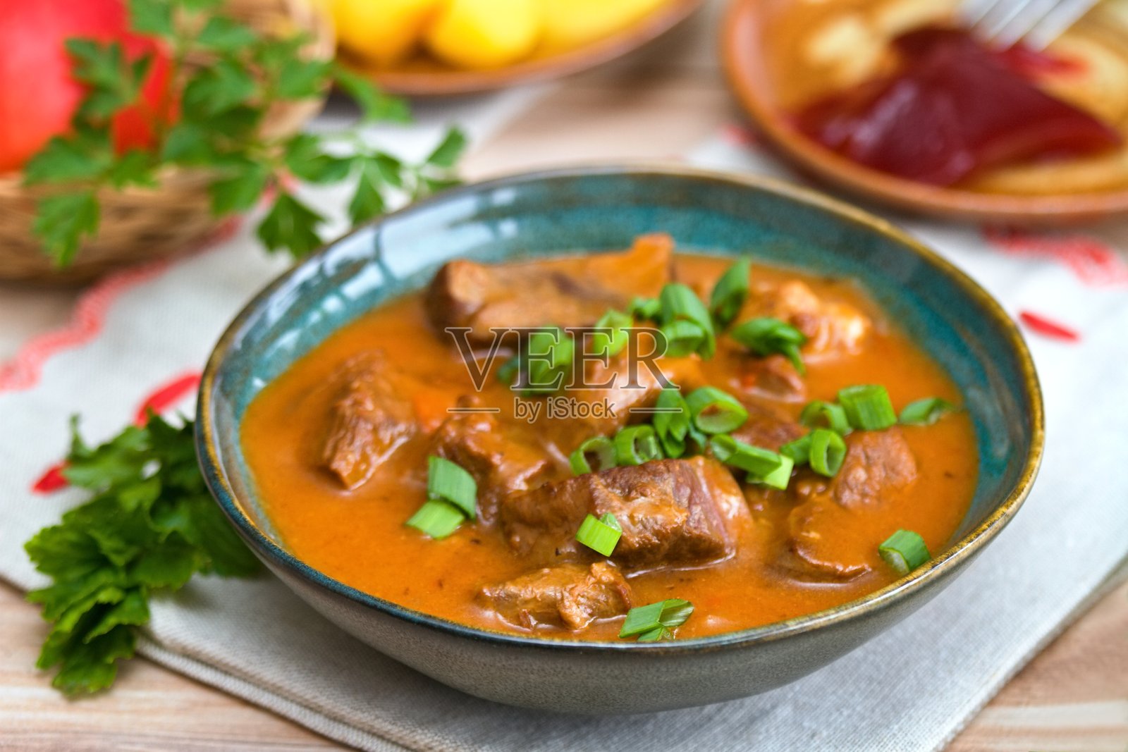 美味的鹿肉炖菜，配有葱，盛在碗中。照片摄影图片