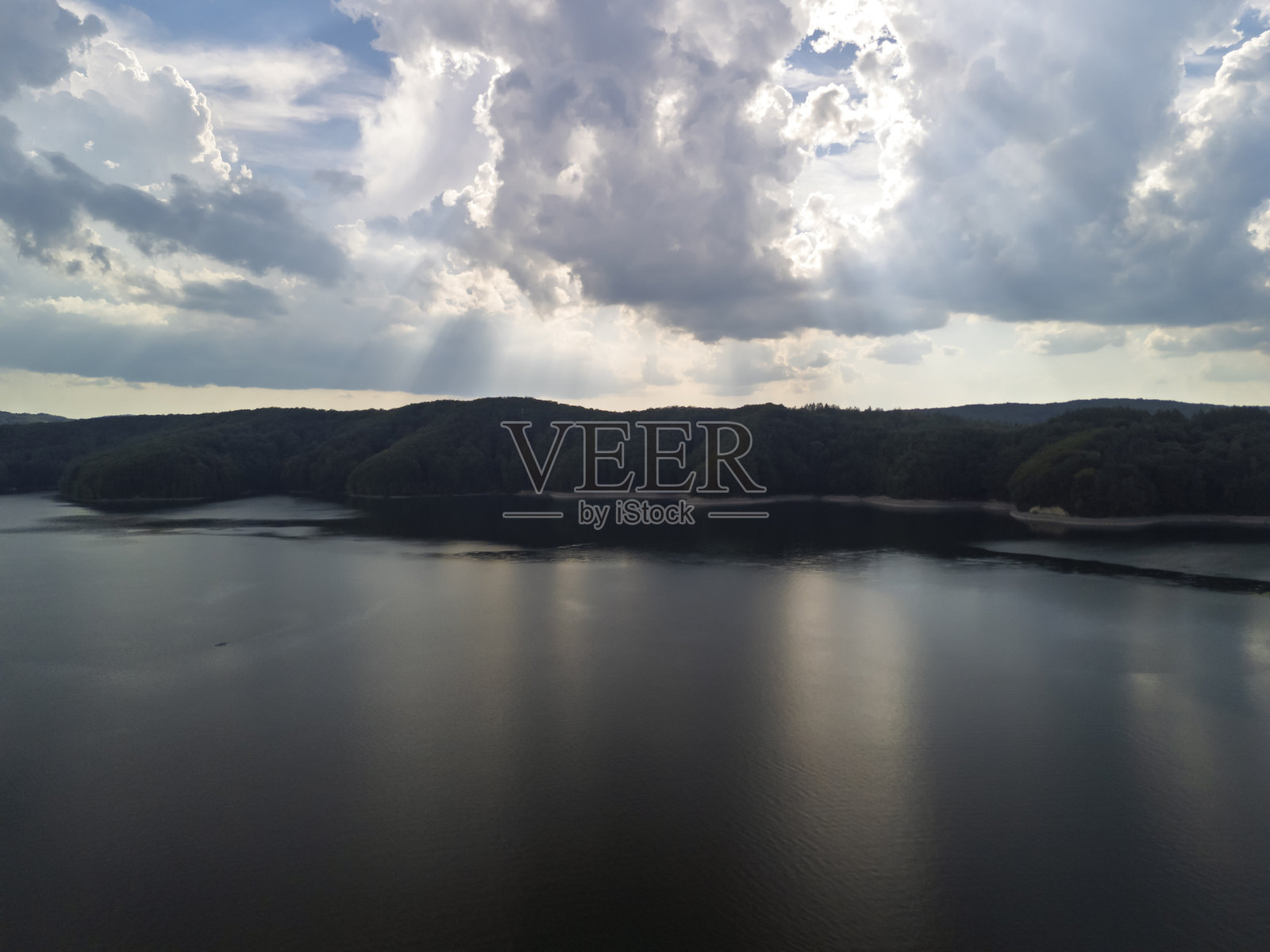 宁静的湖边景色，郁郁葱葱的山丘在多云的天空下。平静的水面映照出自然之美，非常适合放松和户外活动。照片摄影图片