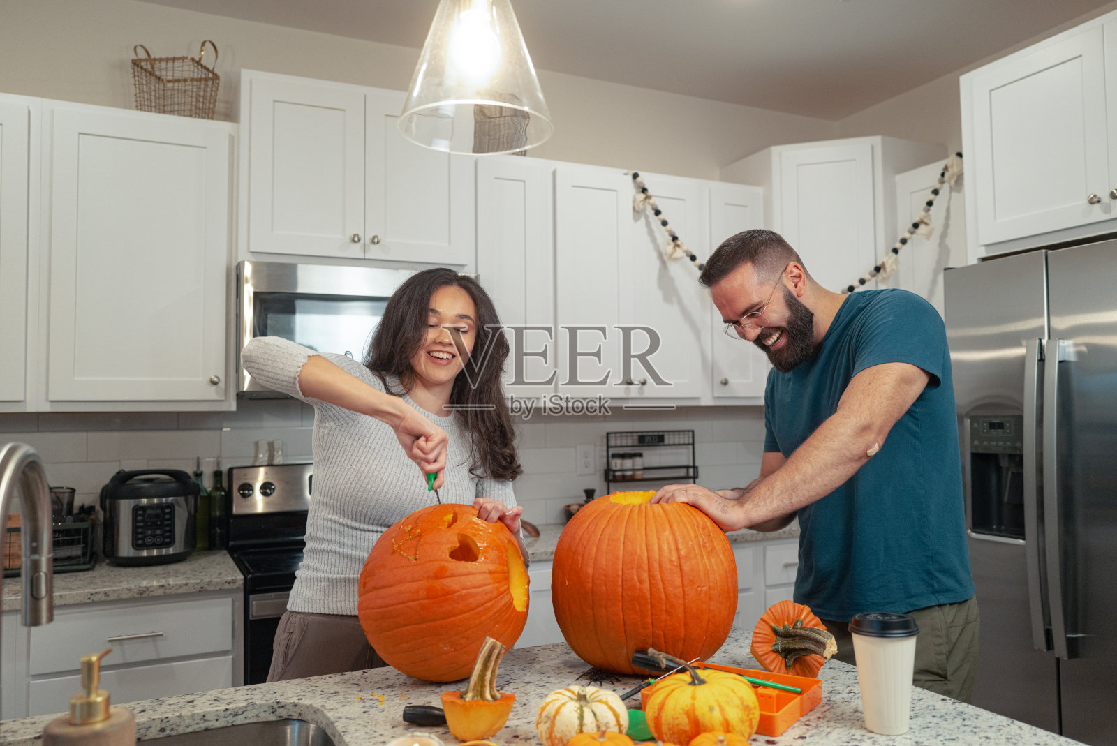 万圣节南瓜雕刻 - 土耳其波斯尼亚男子 - 墨西哥女子 - 一对情侣在雕刻南瓜照片摄影图片