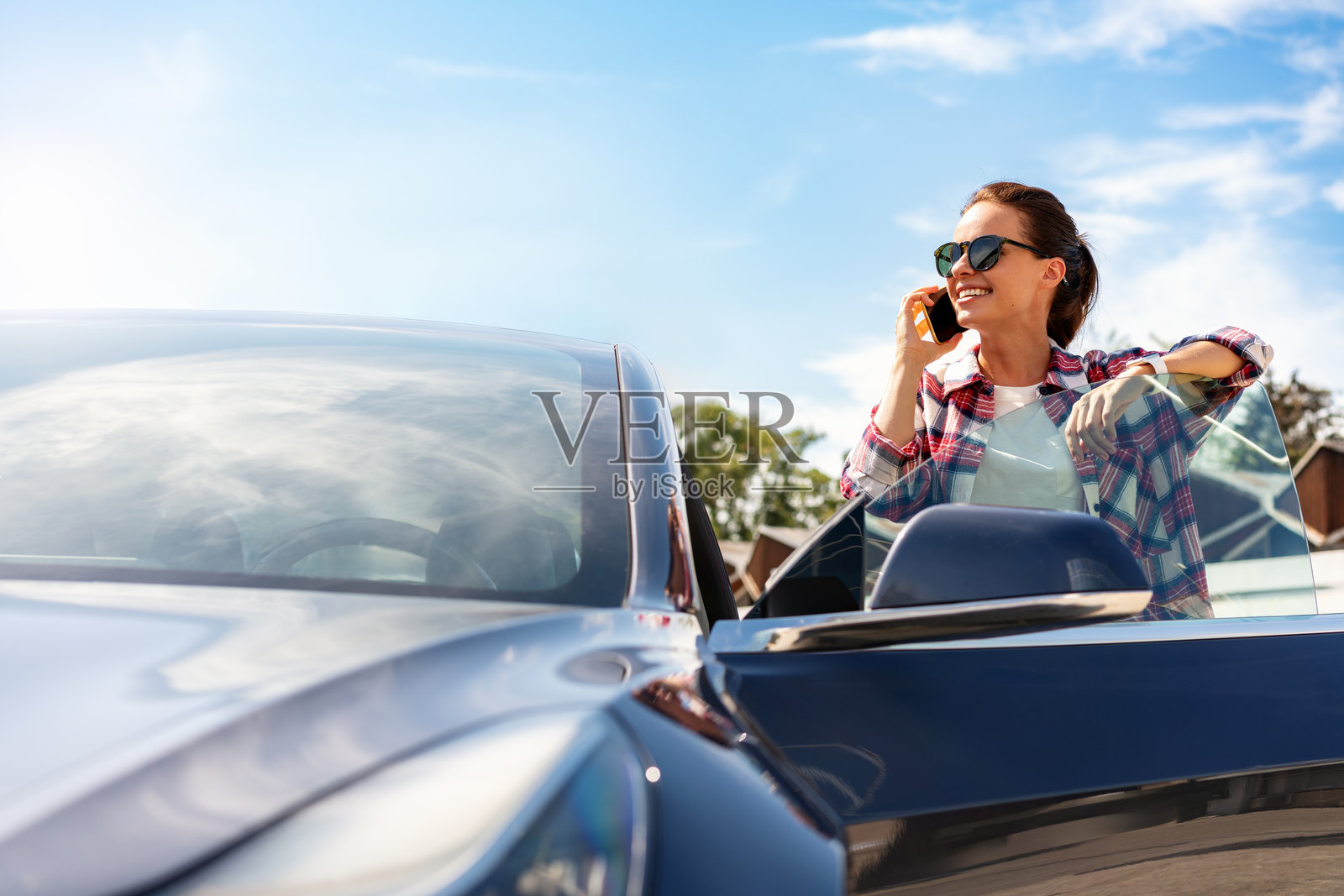夏季户外，一位女性司机站在车旁，正在用手机通话。照片摄影图片