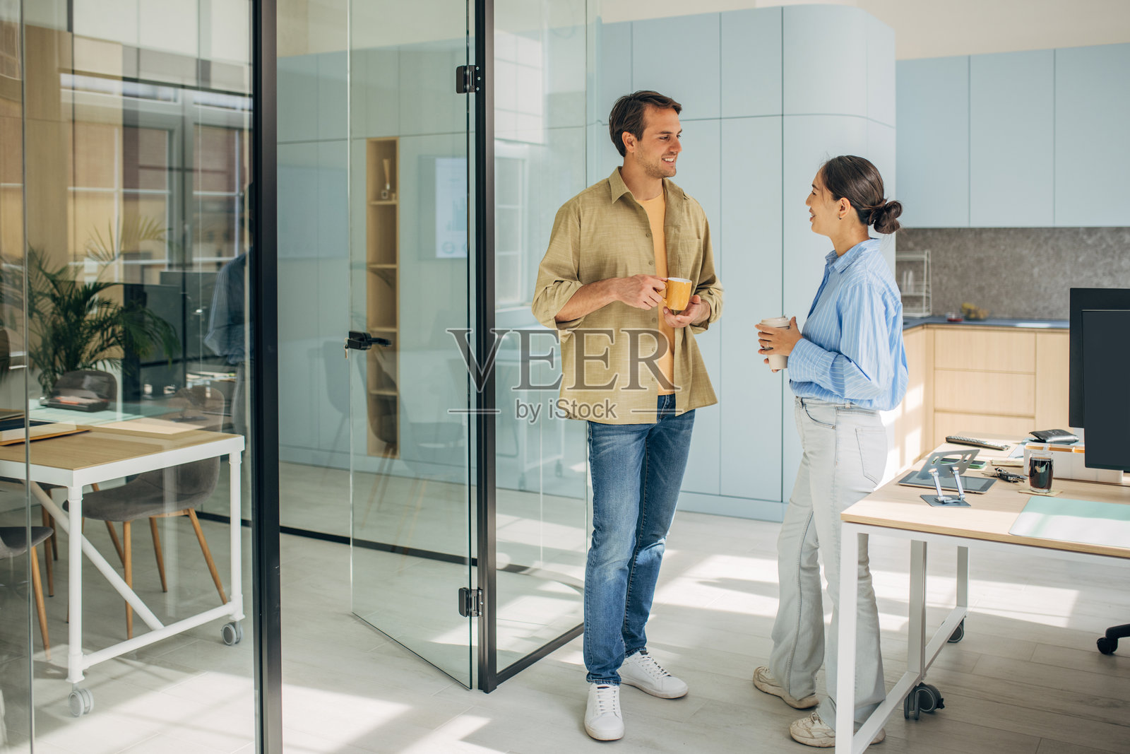 明亮的办公室里，咖啡杯旁的聊天充满了兴奋照片摄影图片