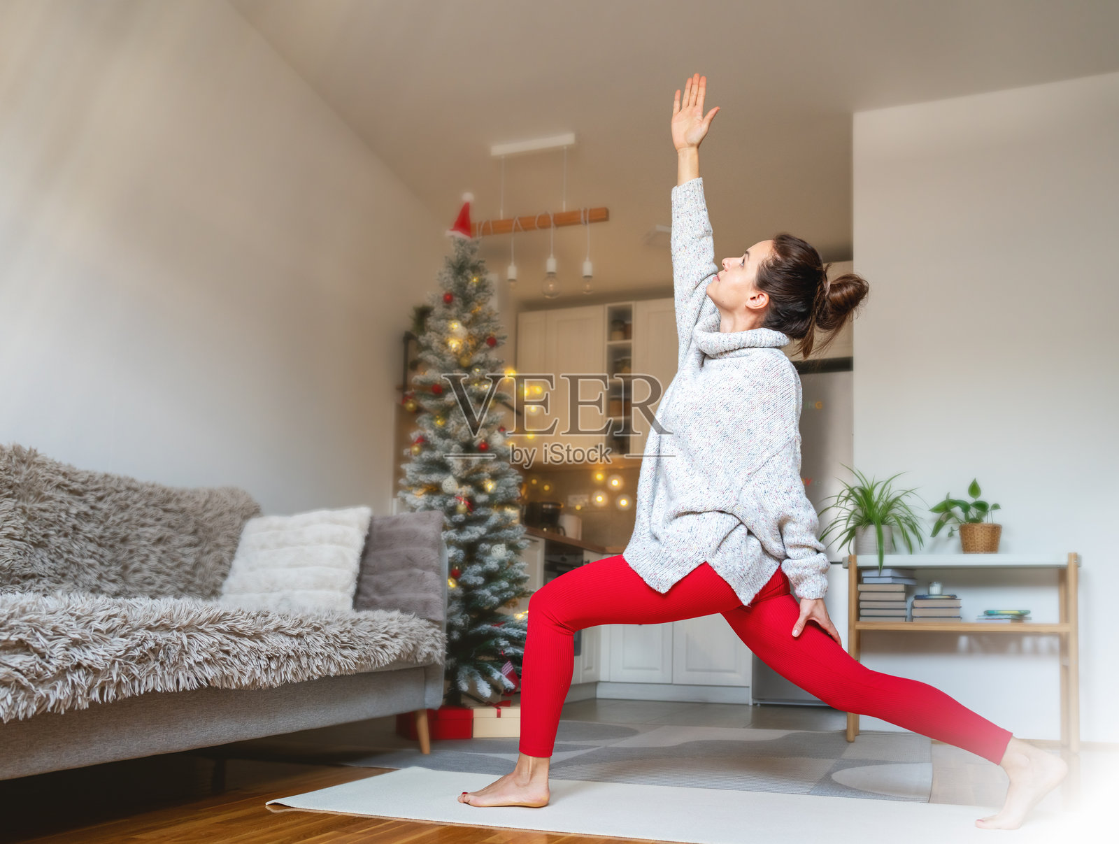 女性在圣诞假期期间在家做瑜伽练习。照片摄影图片