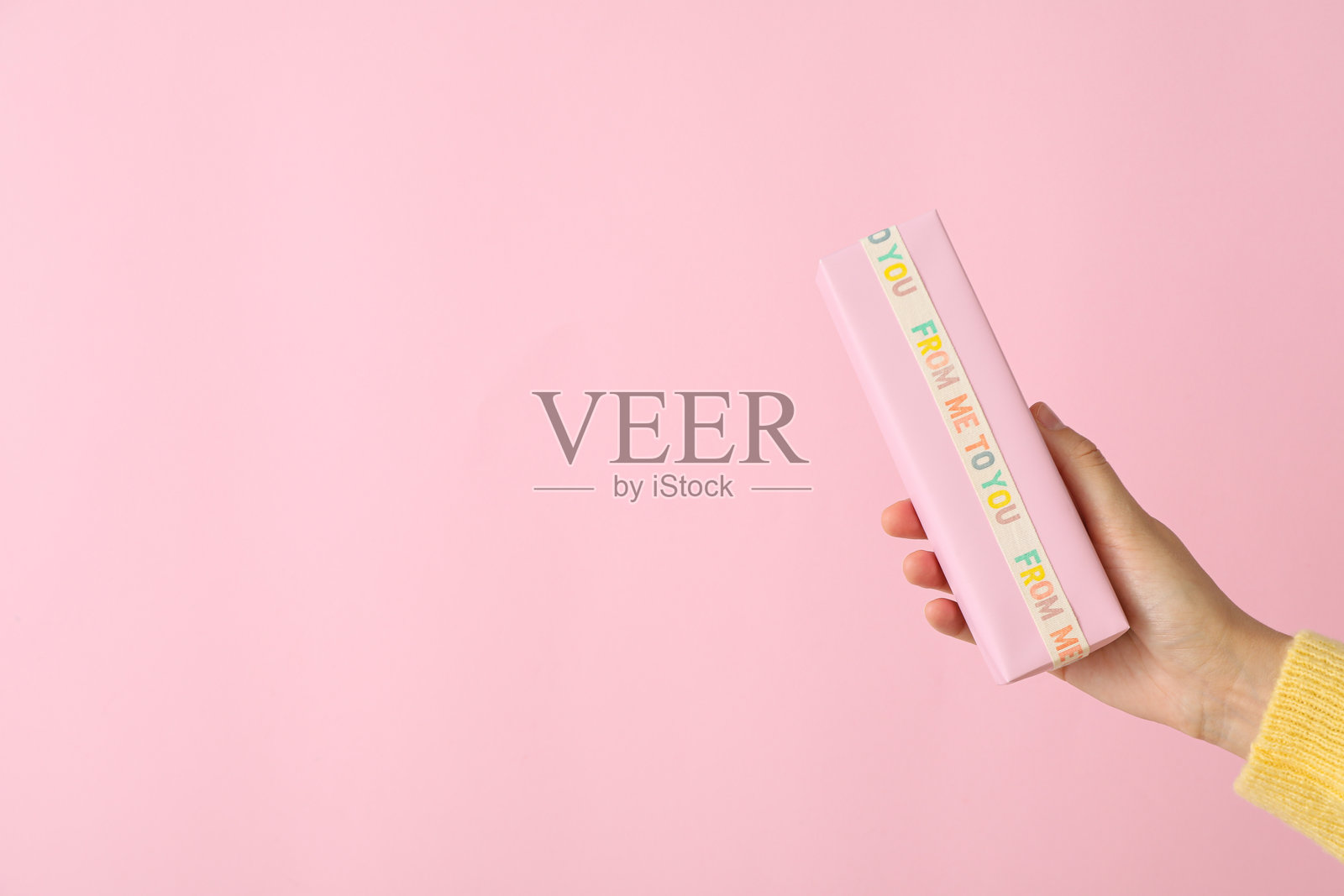 粉色背景上女性手中的礼品盒，留有文字空间照片摄影图片