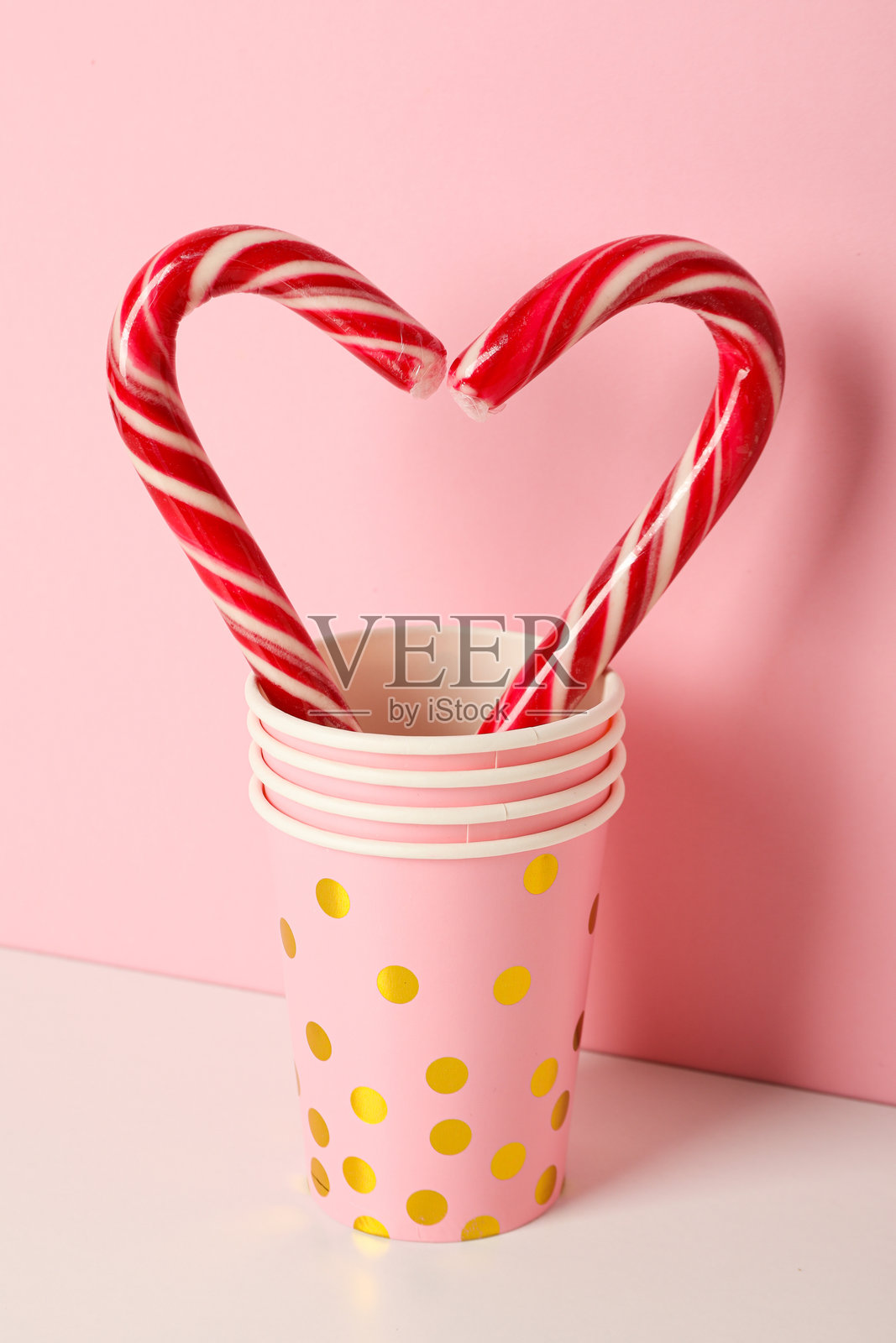 粉色背景上的纸质眼镜和圣诞糖杖照片摄影图片