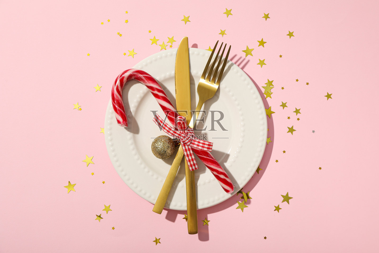 粉色背景上的盘子、餐具和圣诞糖果，俯视图照片摄影图片