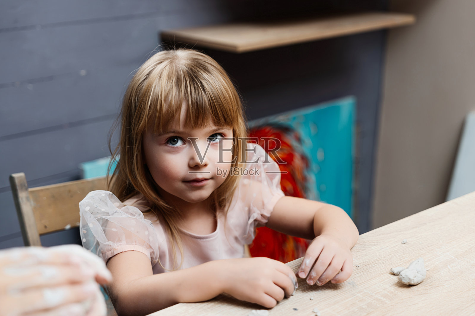 金发女孩坐在艺术空间的木桌旁照片摄影图片