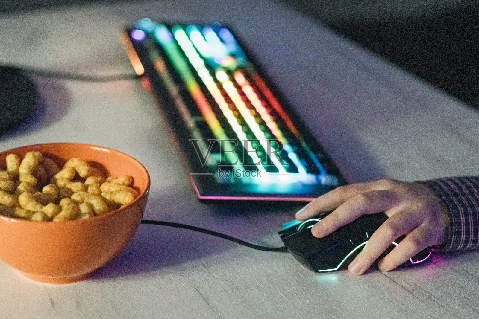 男孩玩电脑游戏时的手部特写，配有RGB电脑键盘和鼠标。儿童游戏成瘾。照片摄影图片