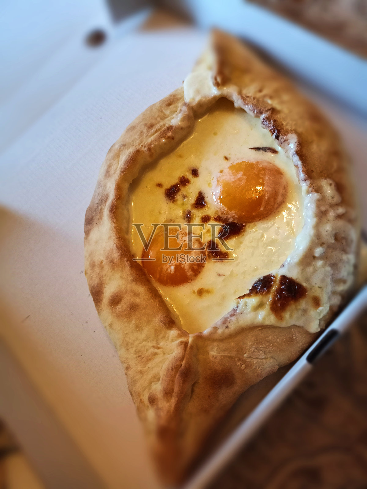 传统且美味的格鲁吉亚菜肴 - 阿贾尔风格的哈恰普里，配有两个蛋黄和奶酪，装在白色盒子里照片摄影图片