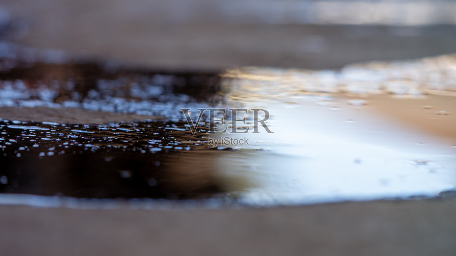 地面上洒落的油水形成了美丽的倒影，在阳光照射下显得格外迷人，留有空白或负空间。照片摄影图片