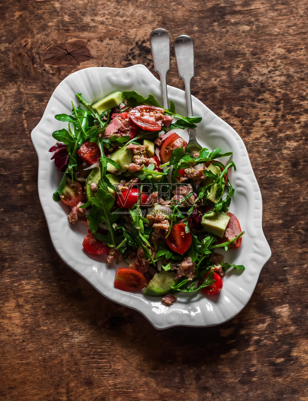 营养丰富的沙拉，配有鳄梨、罐装金枪鱼、樱桃番茄和芝麻菜，背景为木质纹理照片摄影图片