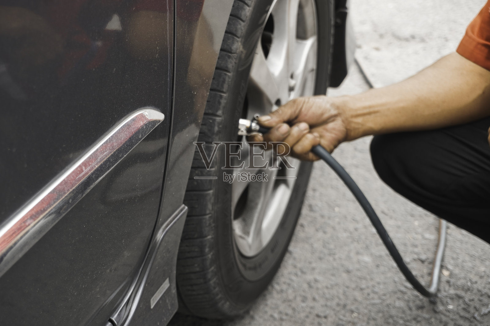 男子驾驶员手动拆卸轮胎阀门氮气盖以检查气压和充气。照片摄影图片