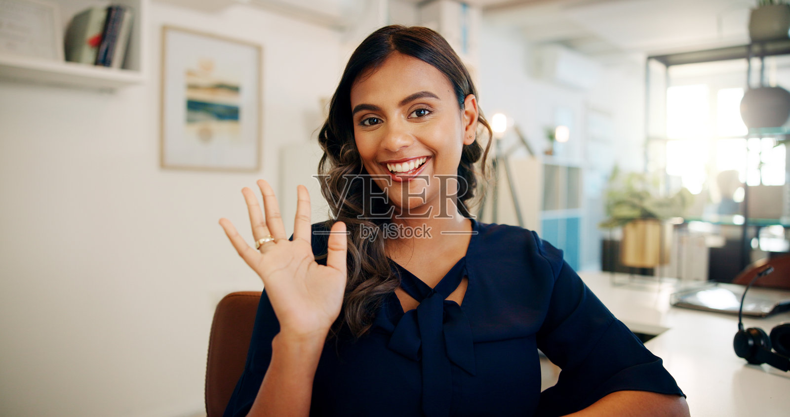 商务女性在办公室进行视频通话，在线会议和研讨会中挥手问候。快乐、微笑，桌子上进行公司虚拟会议，参与网络研讨会和数字讨论。照片摄影图片