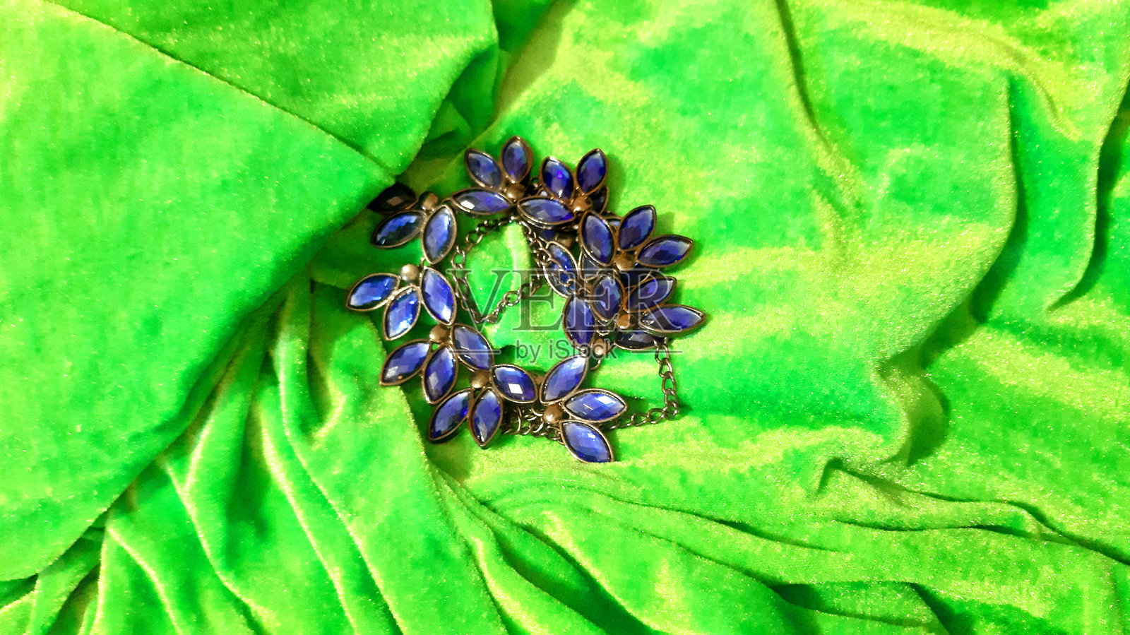 带有蓝色宝石的女性珠宝，背景为绿色纺织品。背景设计，摄影新颖。纺织品，面料模板，现代照片。照片摄影图片