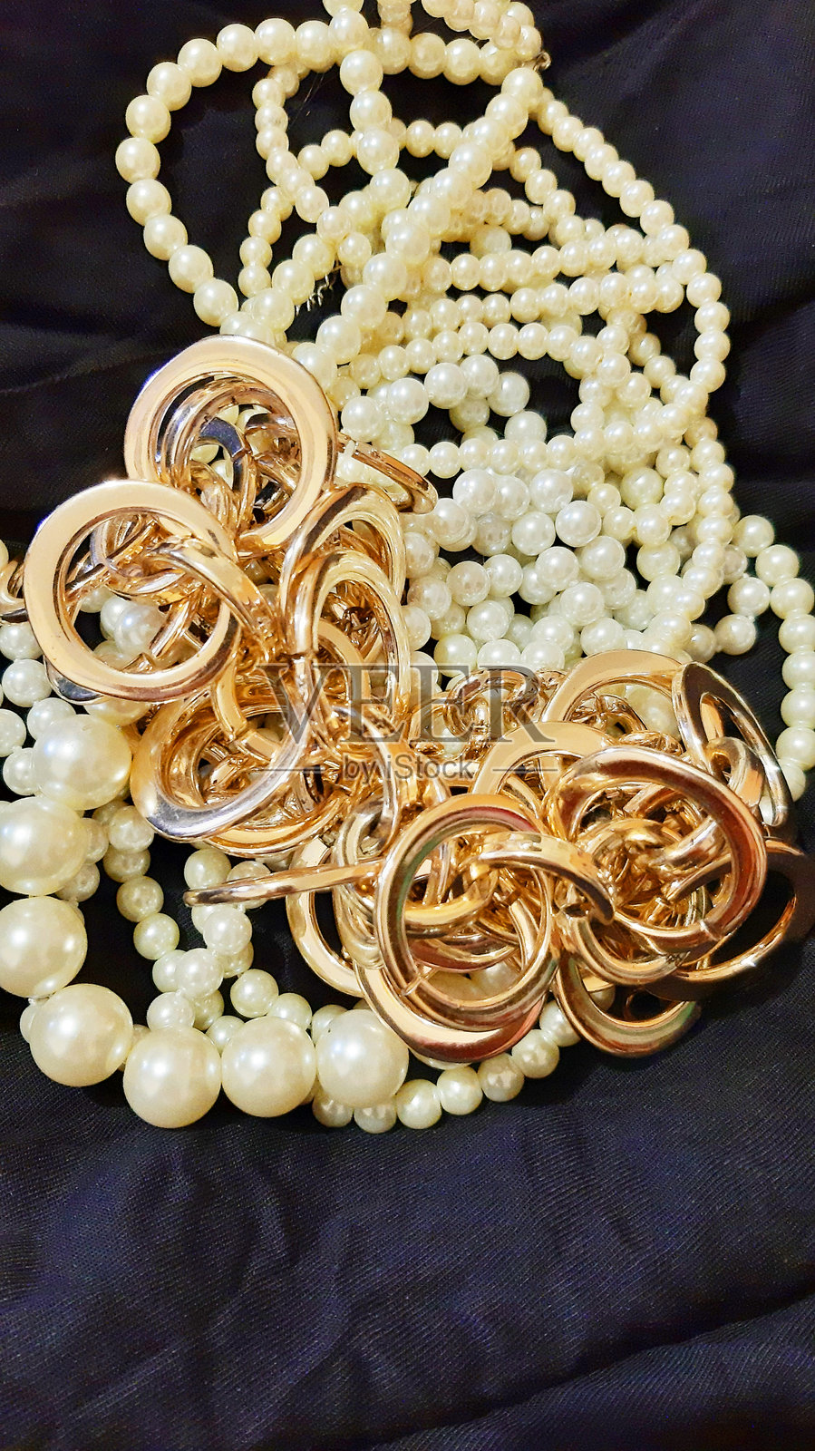 黑色织物上的珍珠女装珠宝和黄金。背景设计，摄影新颖。纺织品，面料模板，现代照片。照片摄影图片