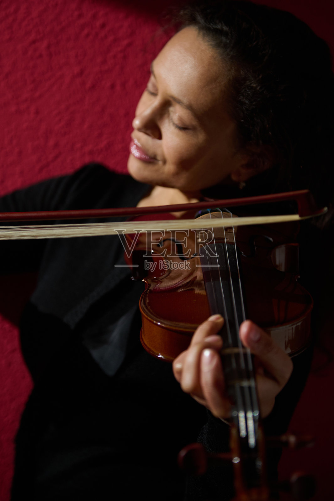 在红色背景下，女人激情演奏小提琴照片摄影图片
