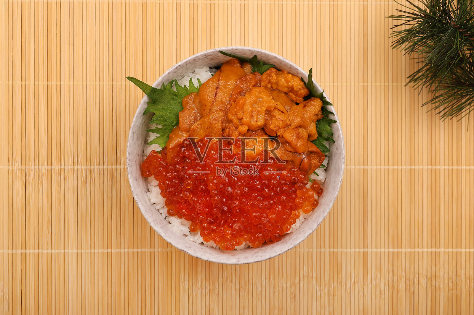 一碗米饭，上面放着海胆和鲑鱼子照片摄影图片