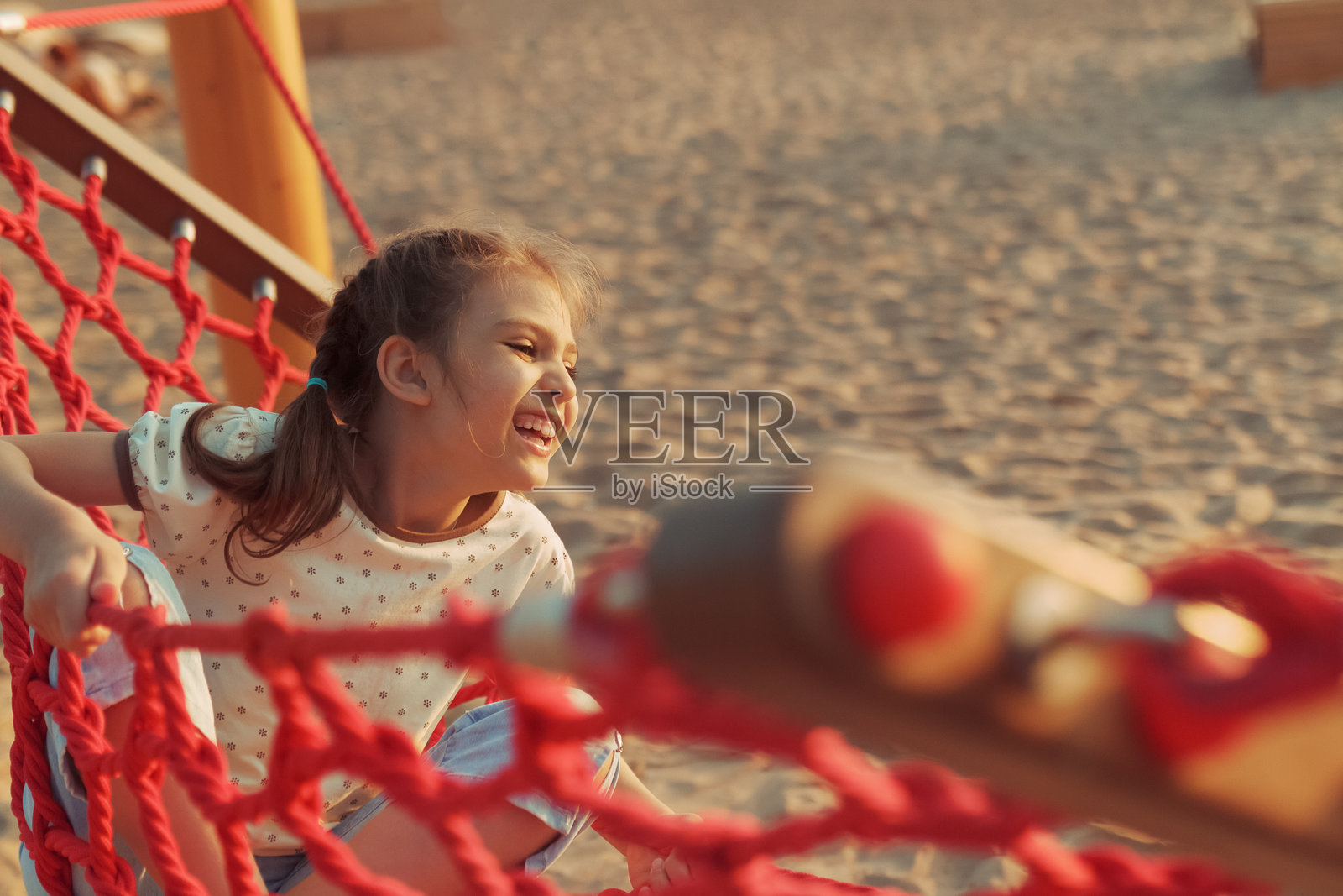 快乐的8岁女孩在海滩上的红色秋千上荡秋千照片摄影图片