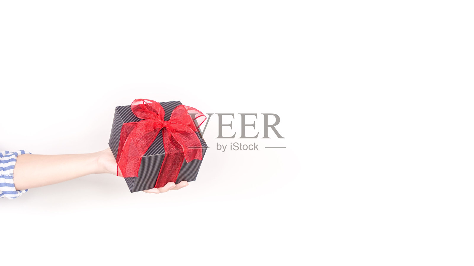 优雅的黑色礼品盒，配有鲜艳的红色丝带蝴蝶结，背景为干净的白色，适合各种场合。照片摄影图片