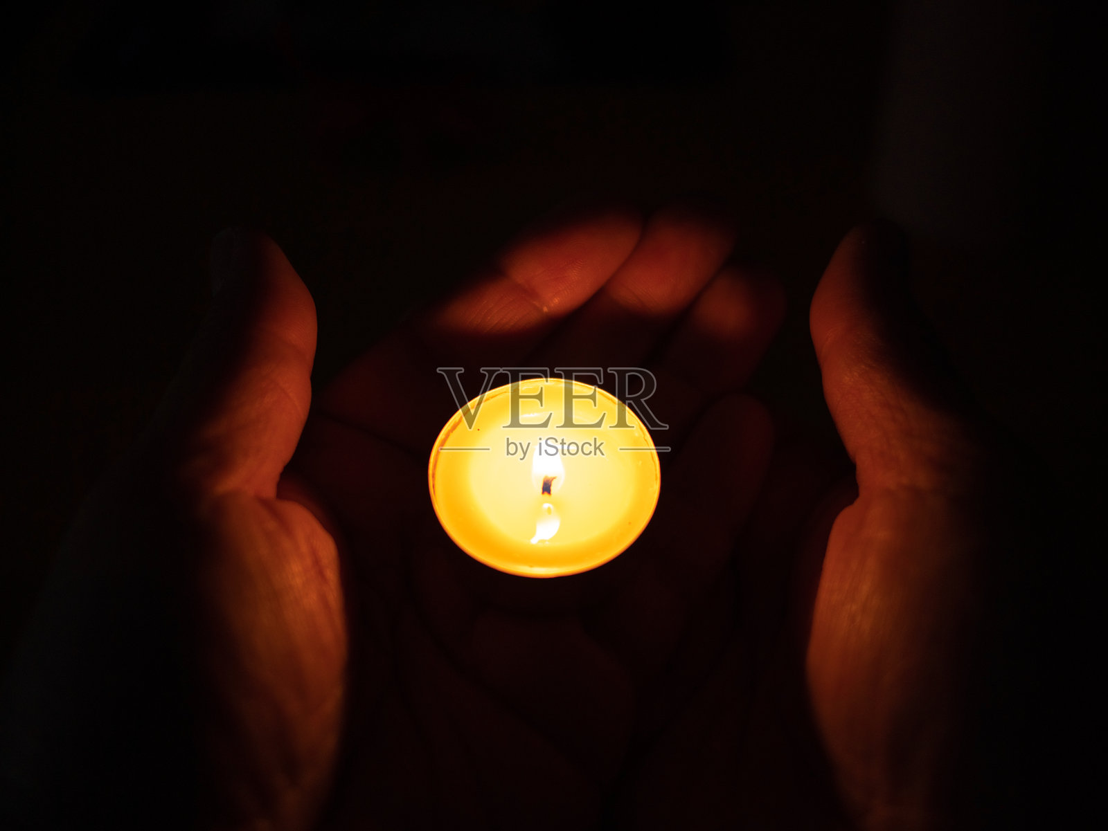 祈祷与信仰 - 手中捧着蜡烛，女人手中的烛光闪烁。祈祷、信仰、宗教概念。照片摄影图片