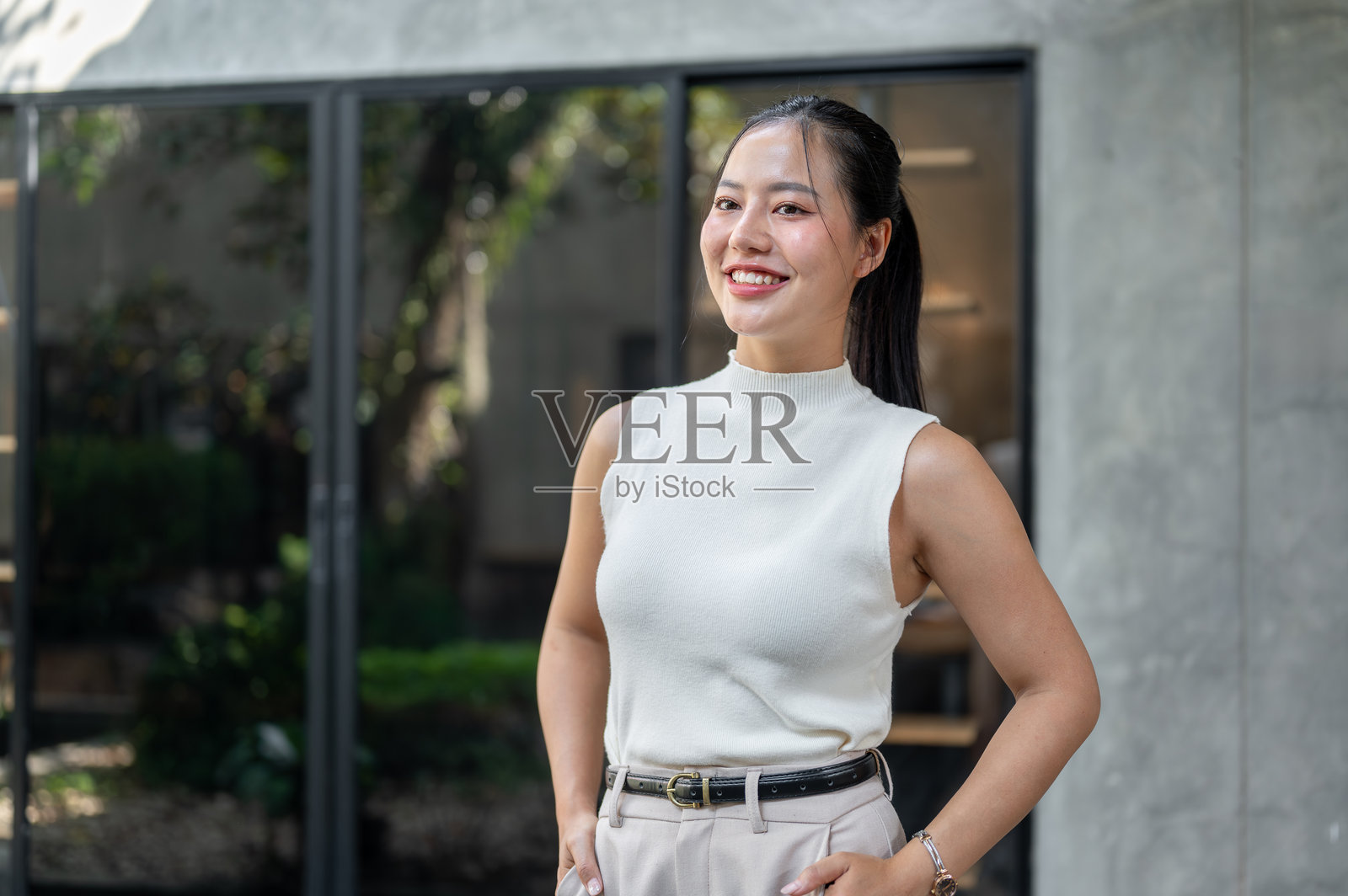 一位微笑的迷人亚洲女性在户外站着，目光投向远方。照片摄影图片