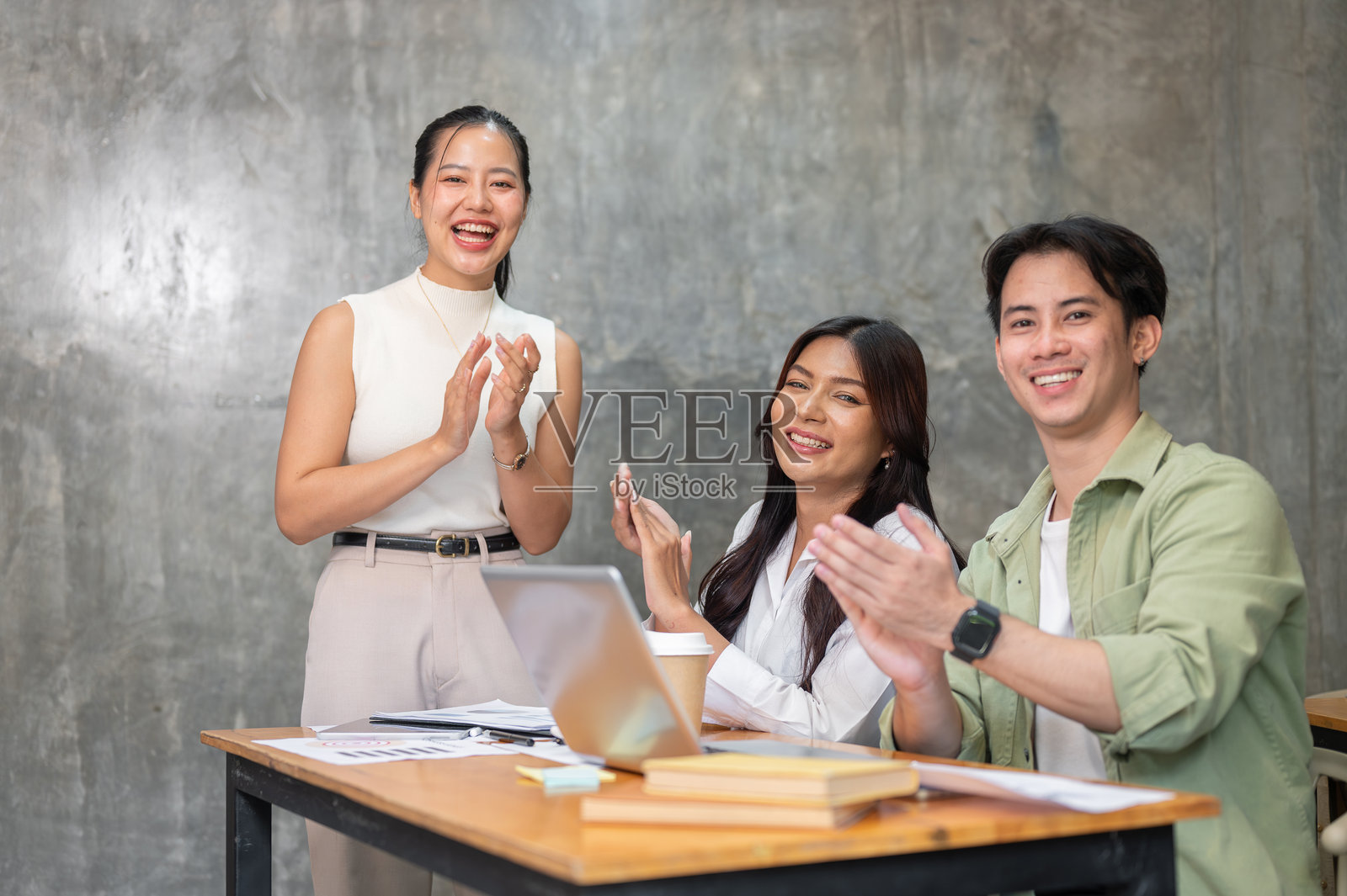 一群年轻的亚洲创业团队成员正在为镜头鼓掌并微笑。照片摄影图片