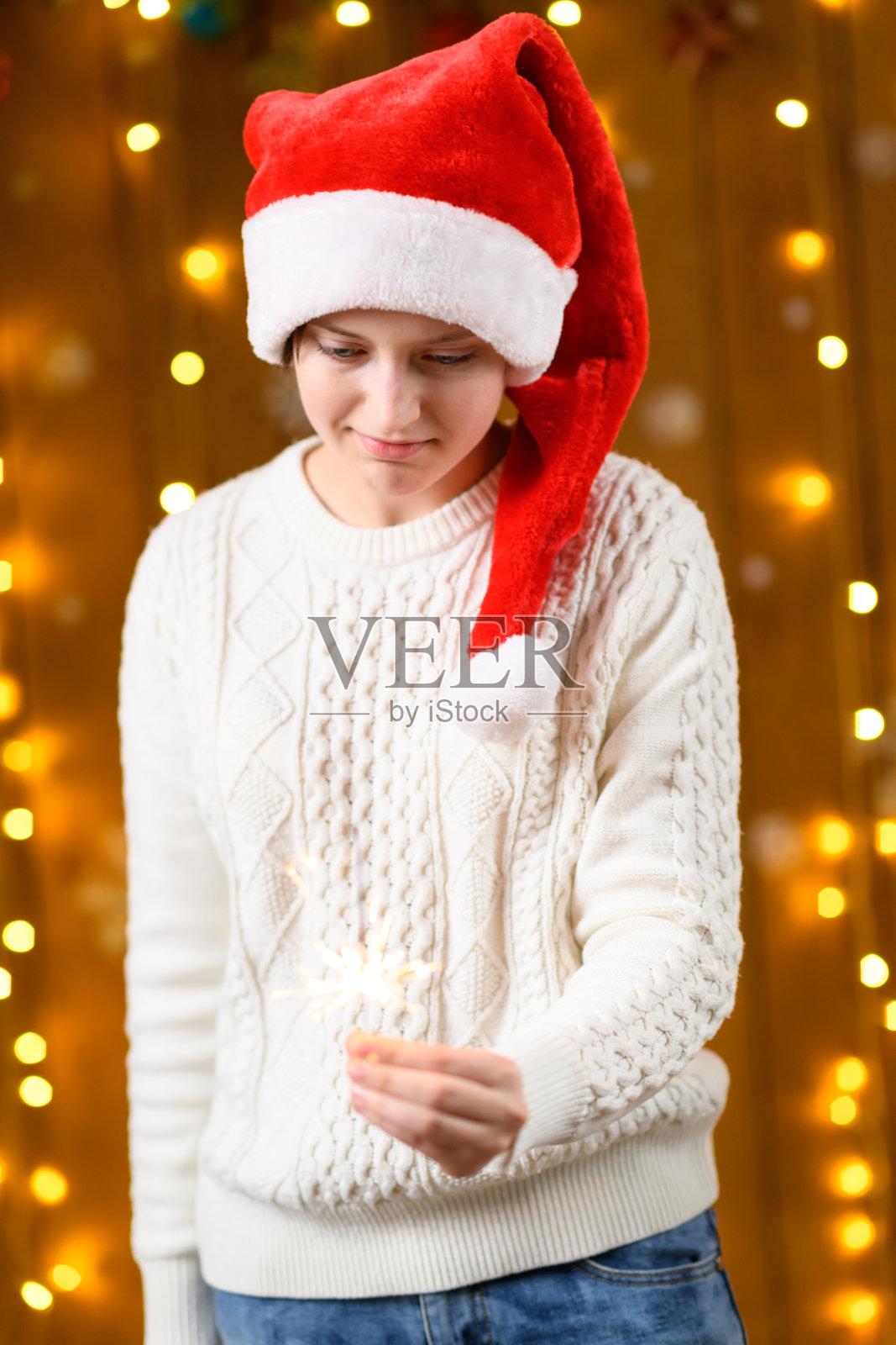 一名少女手持烟花棒，身旁是新年节日装饰、节日灯光和花环。照片摄影图片