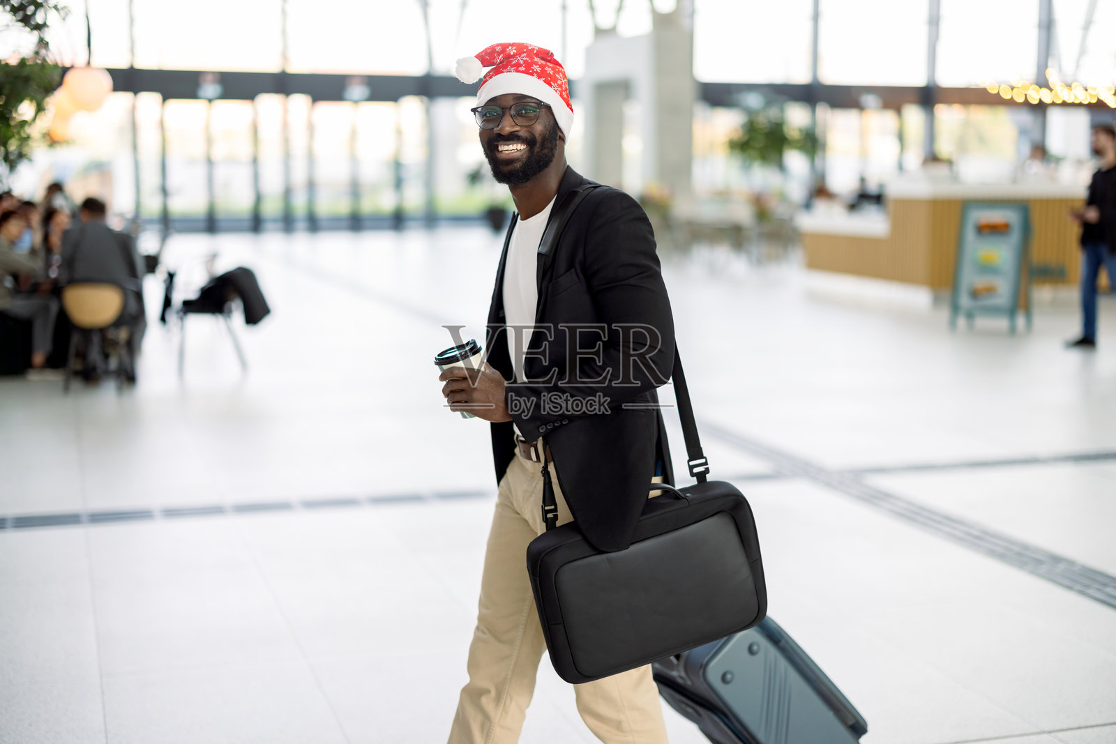 机场内戴着圣诞帽的男子手拿咖啡照片摄影图片