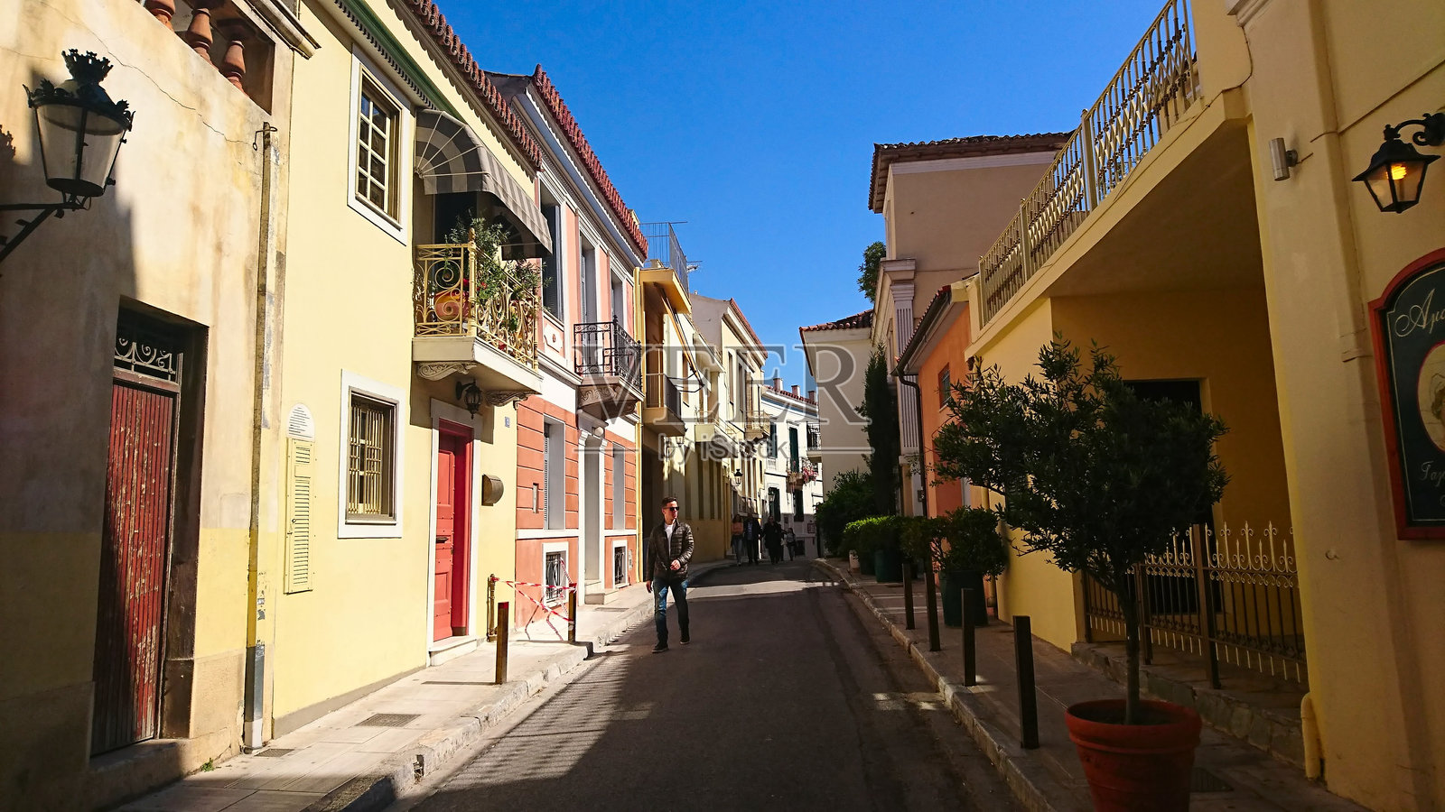 行人走在安静的街道上，周围是色彩斑斓的住宅房屋照片摄影图片