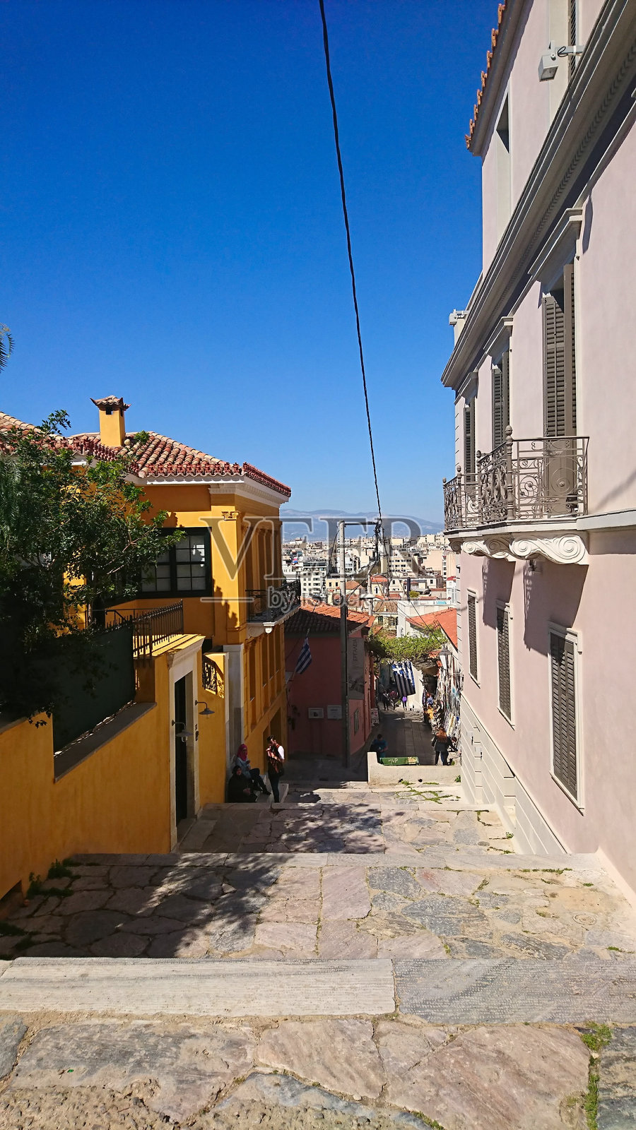 一条普通的小巷，旁边有商店，人们坐在台阶上。照片摄影图片