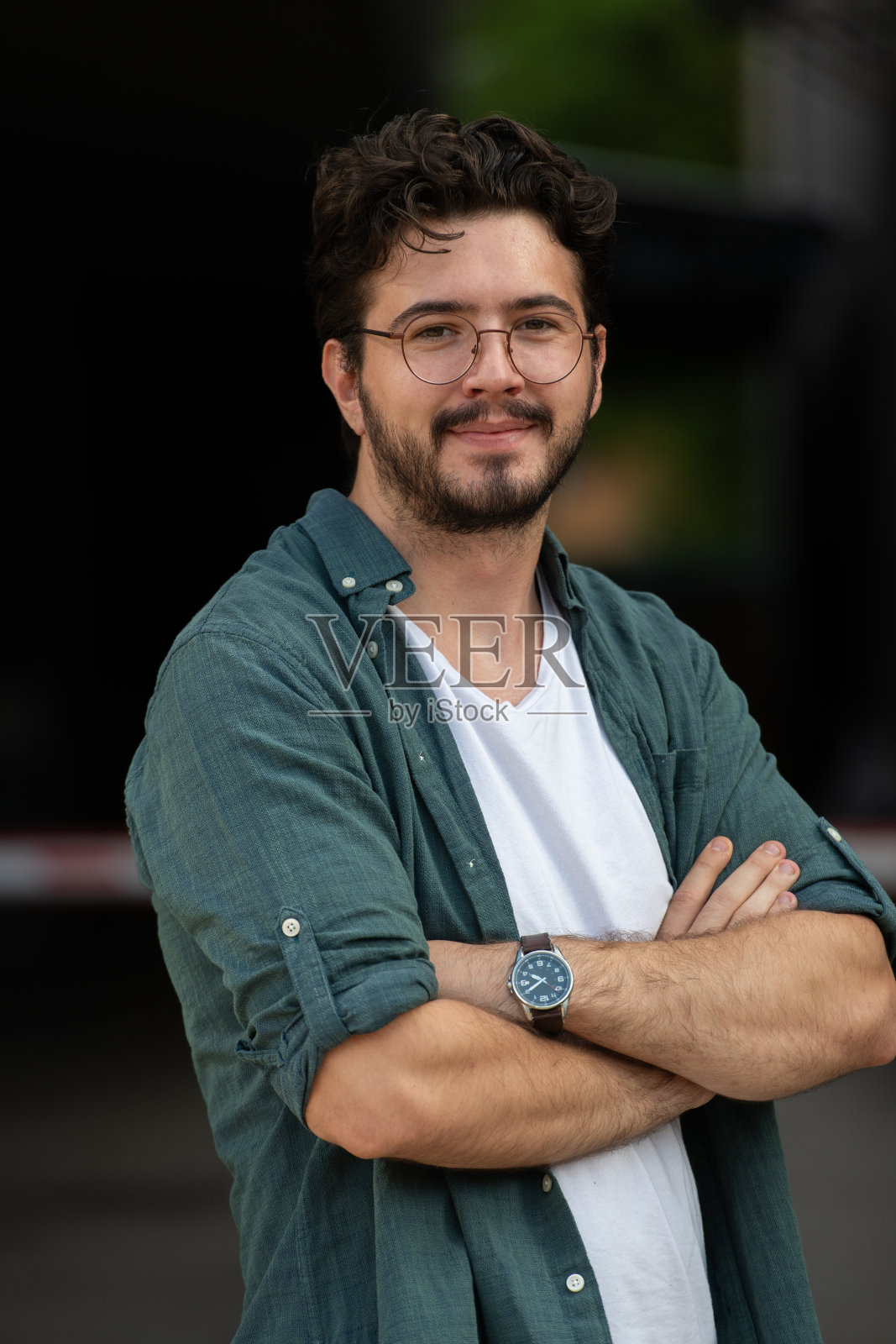 一位成功的年轻商人在户外穿着衬衫，双臂交叉，自信地微笑。照片摄影图片