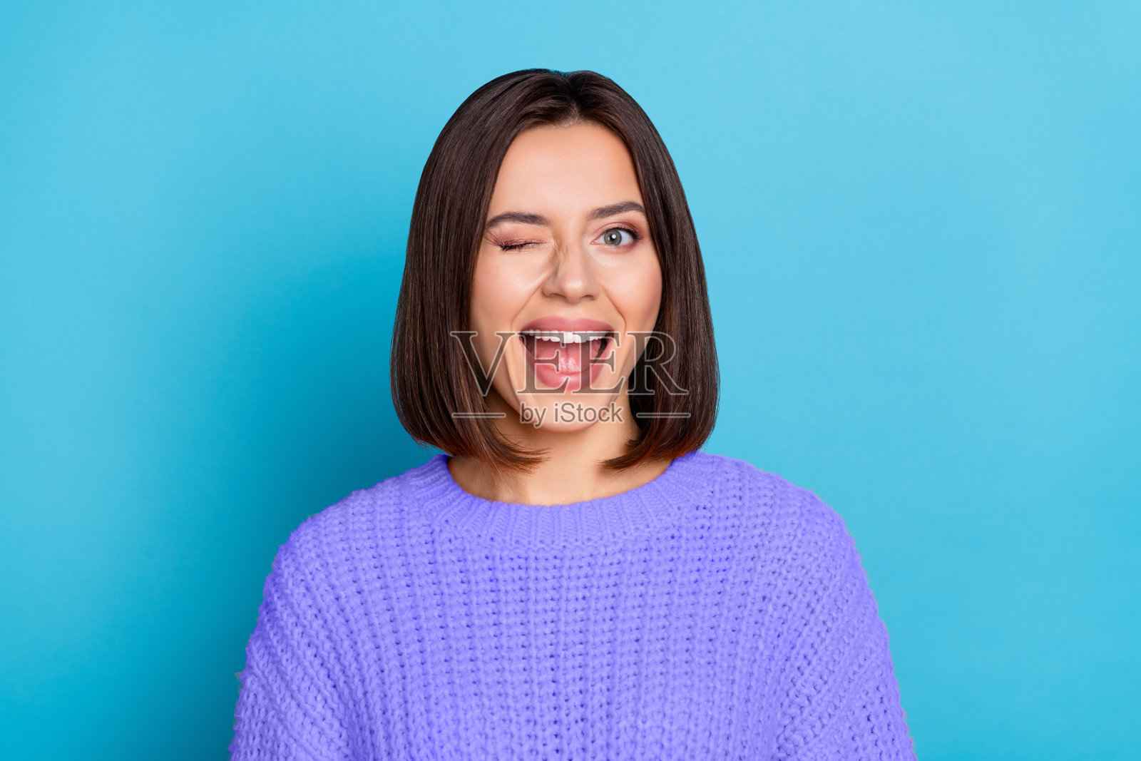 迷人、调皮、愉快的女孩在明亮的蓝色背景下眨眼，心情很好。照片摄影图片