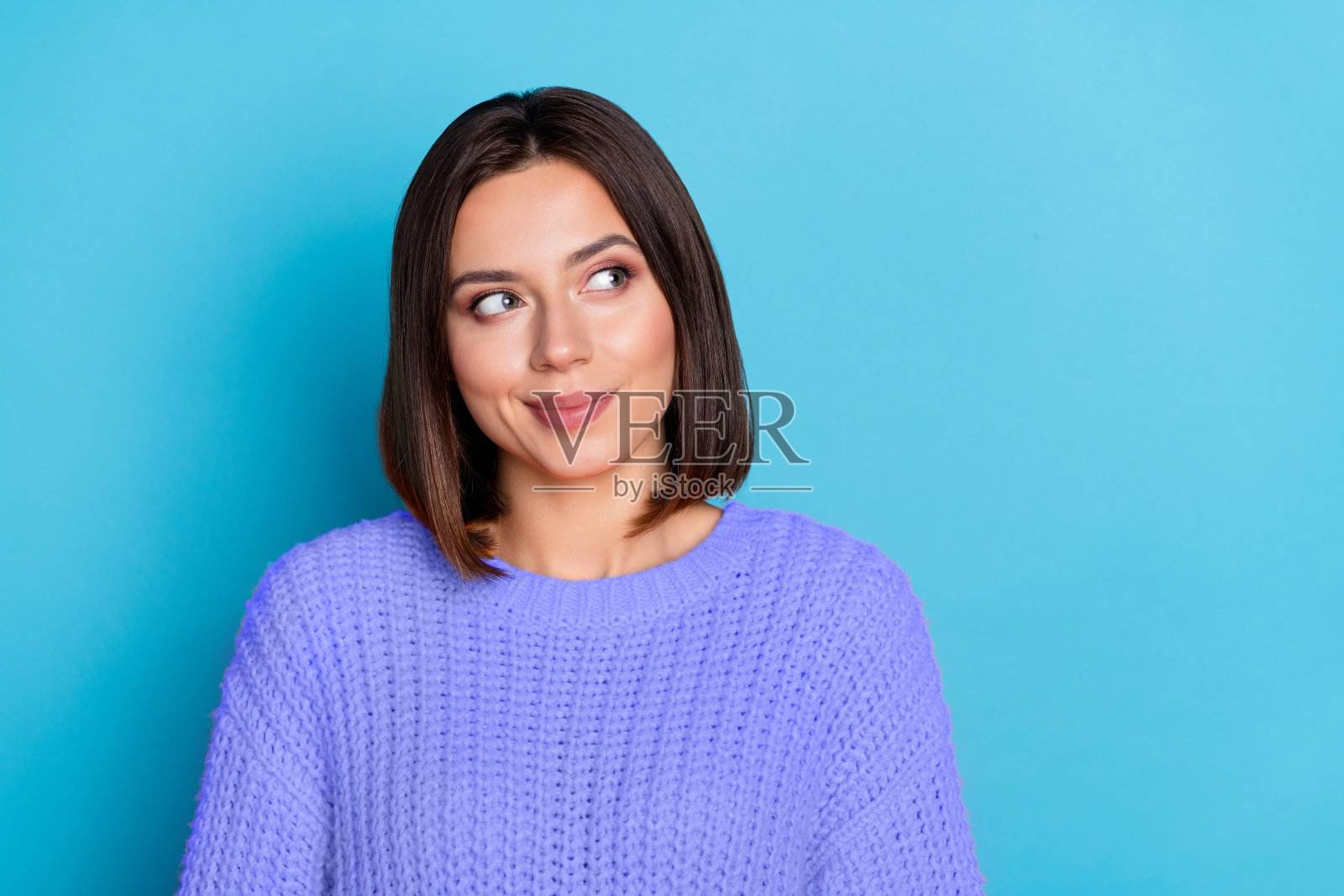 迷人、愉快、困惑的女孩肖像，正在思考空白空间，背景为明亮的蓝色。照片摄影图片