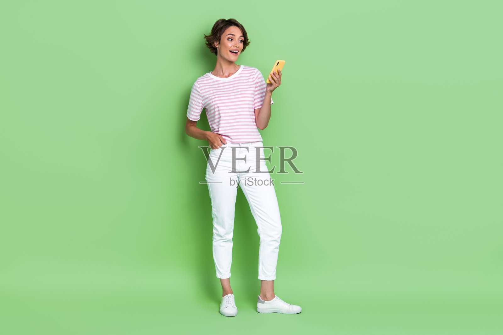 全身照的积极博主手持电话设备，聊天评论新闻，背景为空白的绿色空间。照片摄影图片
