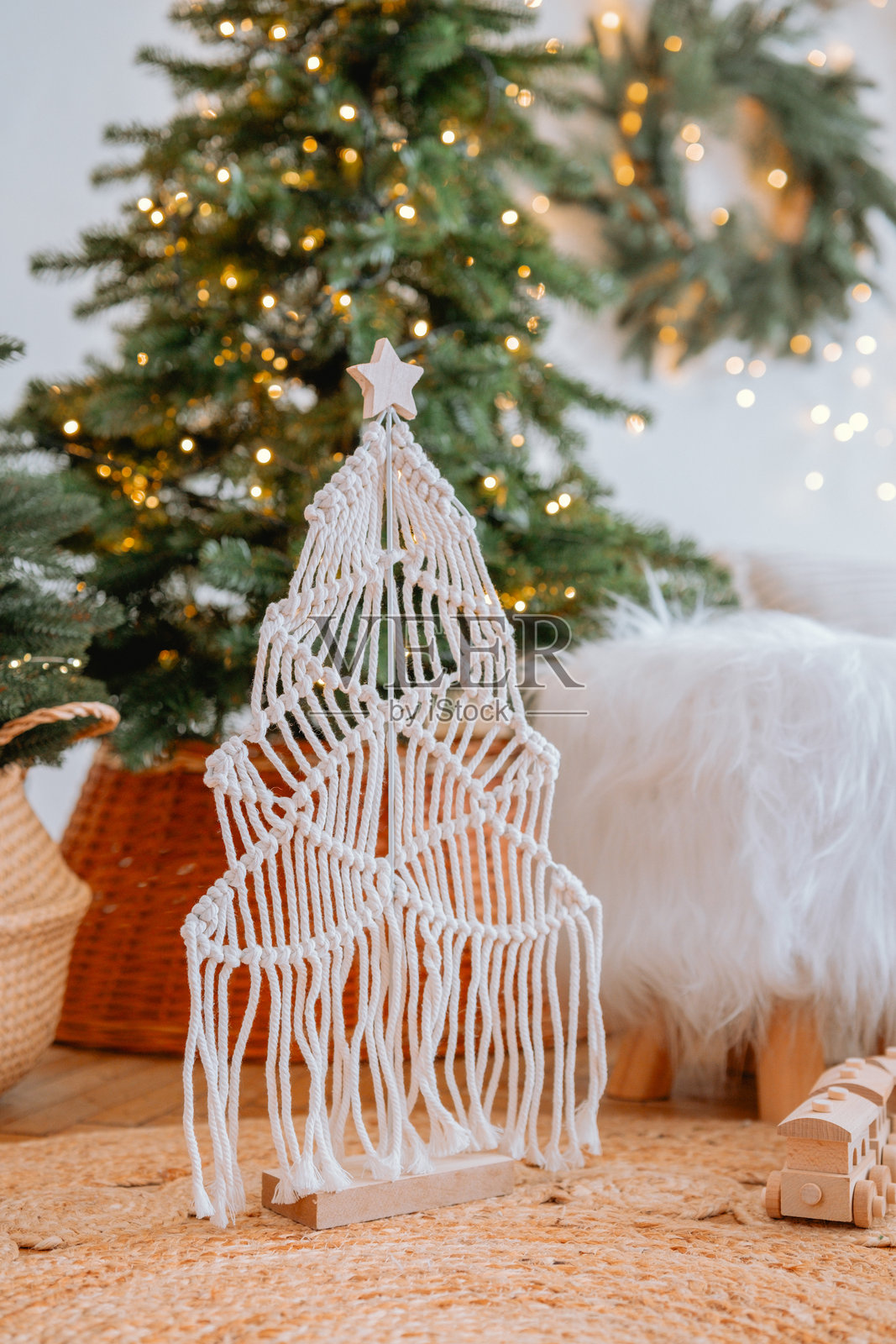 装饰性的挂绳圣诞树，配有节日灯饰和绿植，置于温馨的房间中照片摄影图片