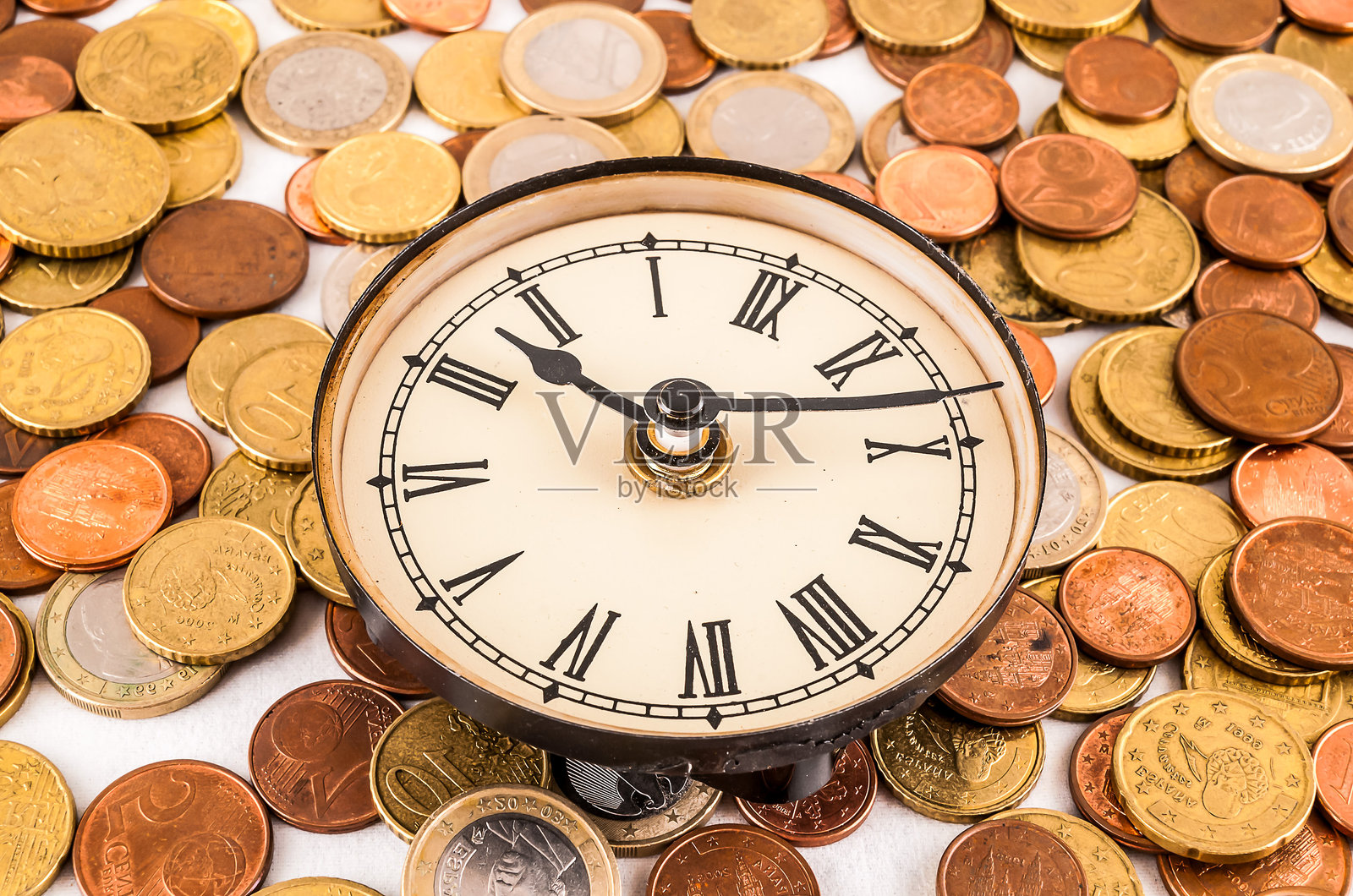 一个带有罗马数字的时钟被一堆硬币包围着照片摄影图片