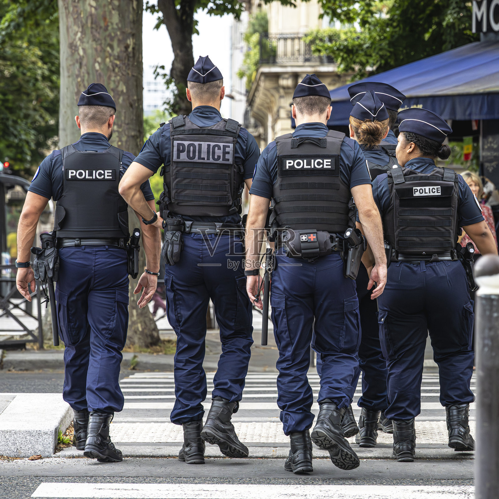 身穿制服的警察徒步巡逻，在法国巴黎的街道上提供安全保障。照片摄影图片