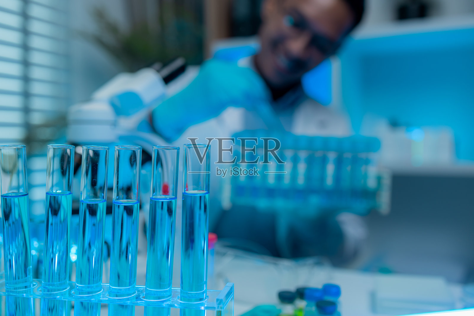 一位科学家在实验室的熟悉环境中舒适地工作，一名科学研究人员正在研究一种液体物质以撰写报告，试管，化学品，药物照片摄影图片