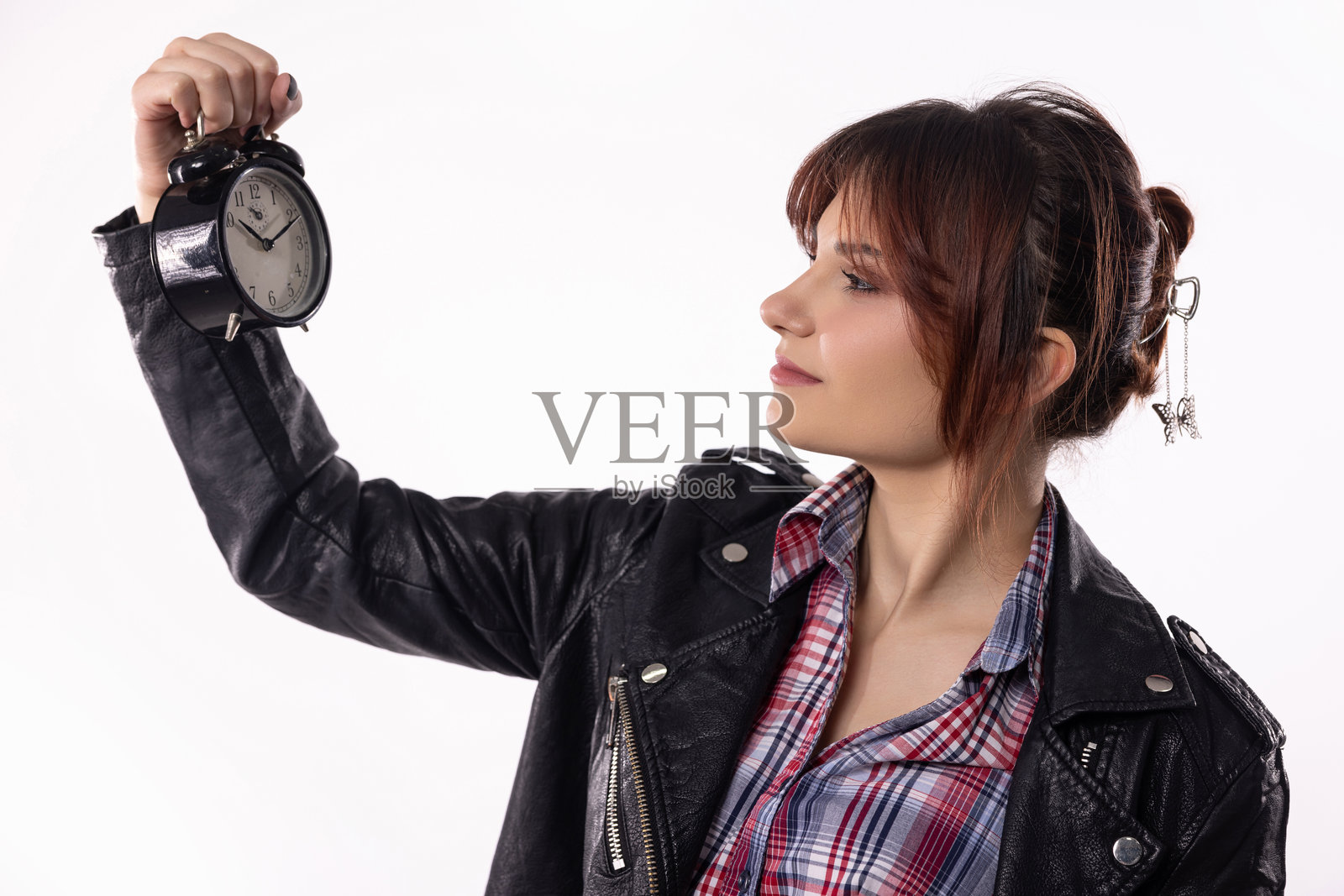 深思熟虑的年轻女性穿着时尚服装，手握闹钟，反思时间照片摄影图片