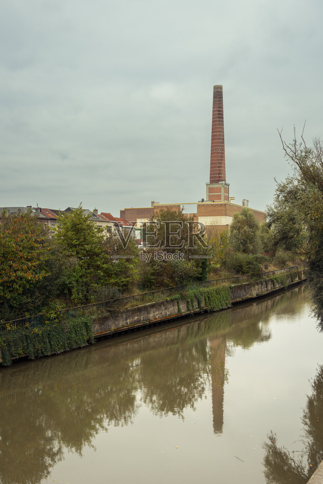 比利时弗拉芒地区根特的工厂烟囱倒映在水中。镜像画面。水的倒影。工业根特。工厂。照片摄影图片