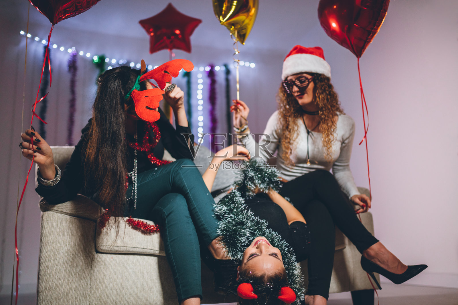 朋友们享受着充满节日气氛的圣诞庆祝活动，周围有气球和节日装饰。照片摄影图片