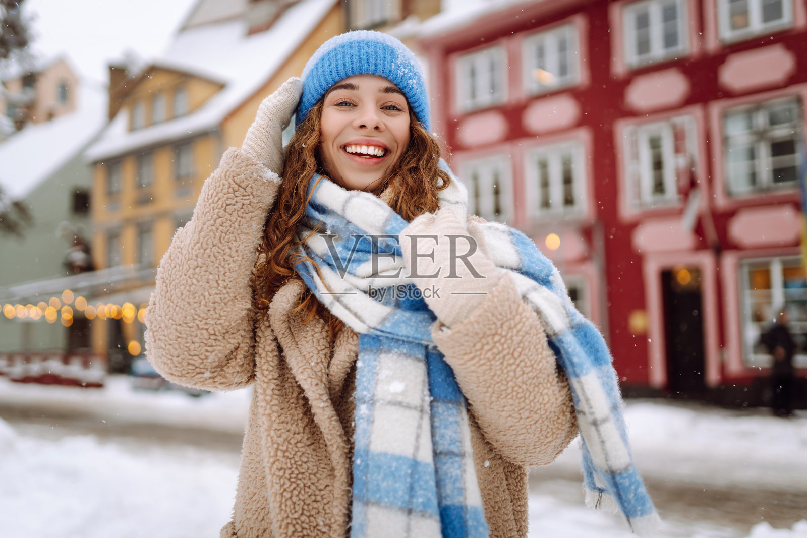 穿着冬季衣物的快乐女性在街上行走。照片摄影图片