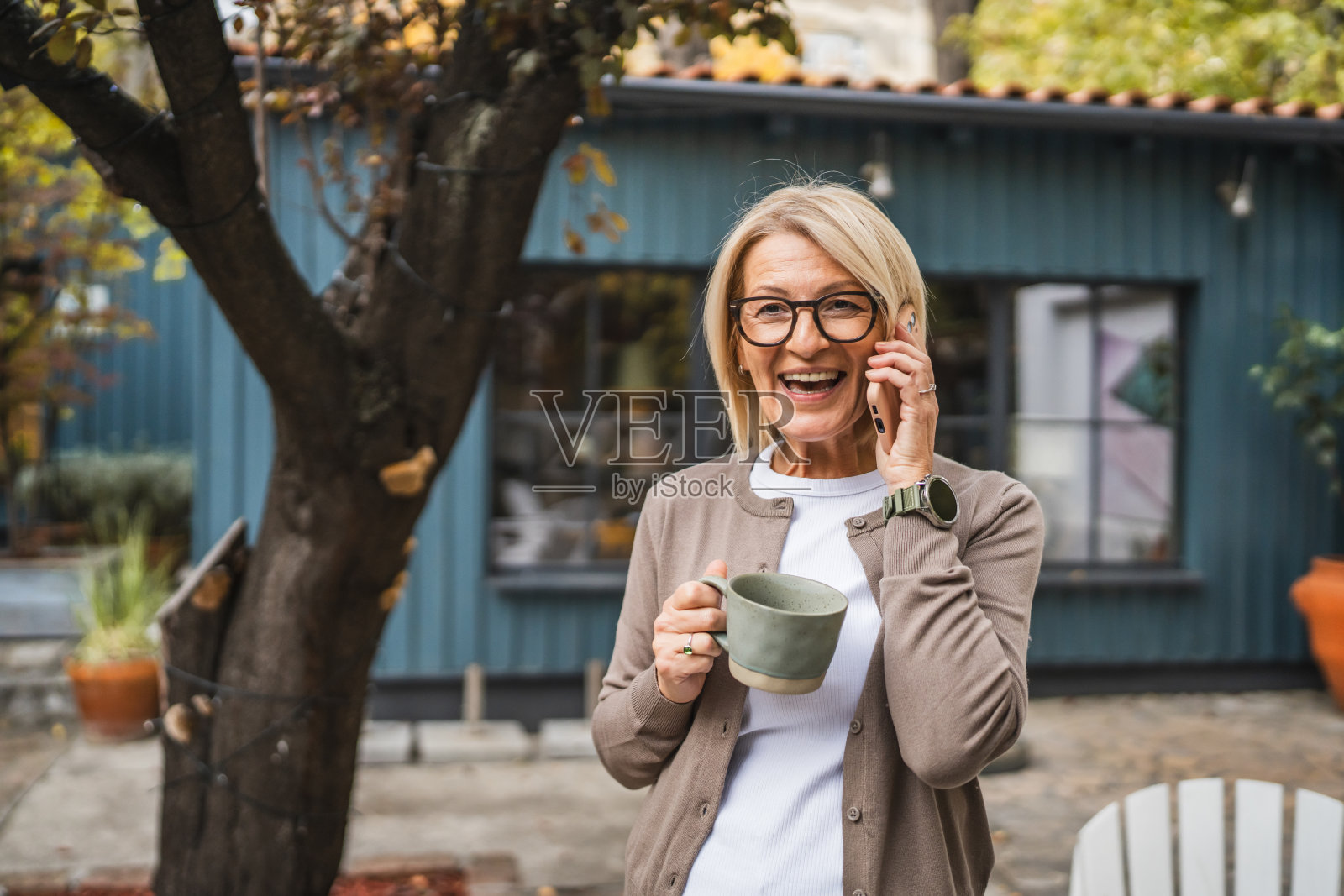 快乐的成熟的女性享受咖啡并在手机上交谈照片摄影图片