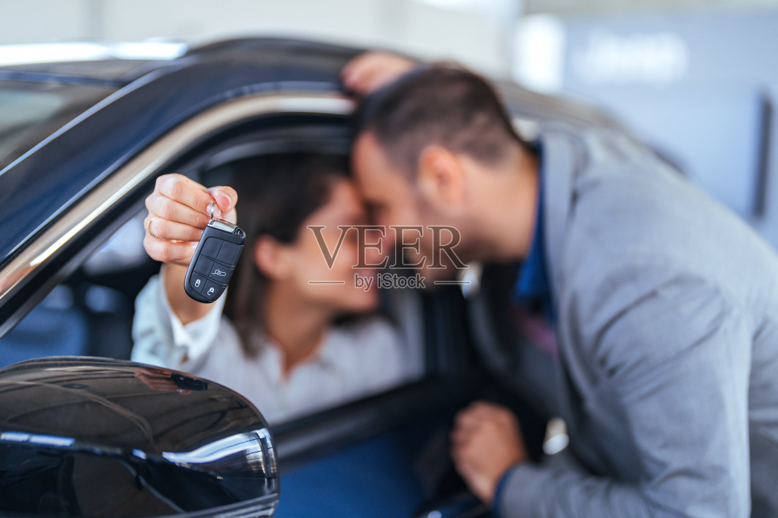 快乐的情侣庆祝新车购买，做出钥匙手势照片摄影图片