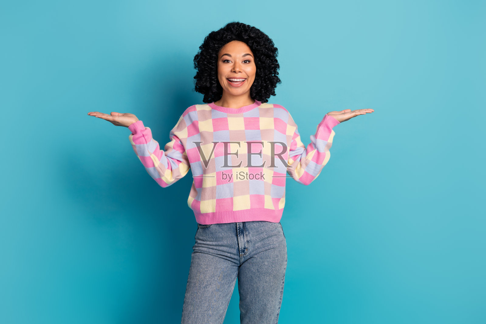 可爱的年轻女士在蓝色背景下穿着时尚的粉色格子服装，手持空白空间的照片肖像。照片摄影图片