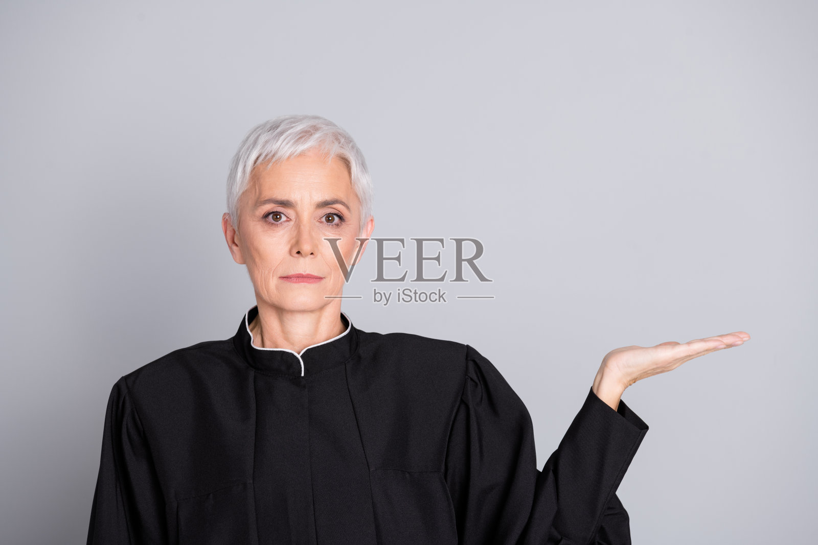 智慧的女性法官手持空白空间示范，背景为灰色。照片摄影图片