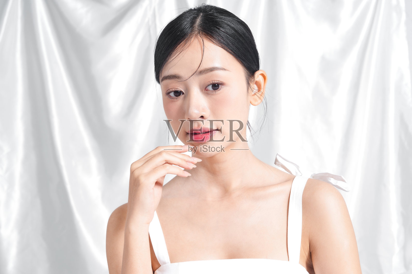 身穿白色裙子的年轻女性美丽肖像，背景为布料。照片摄影图片