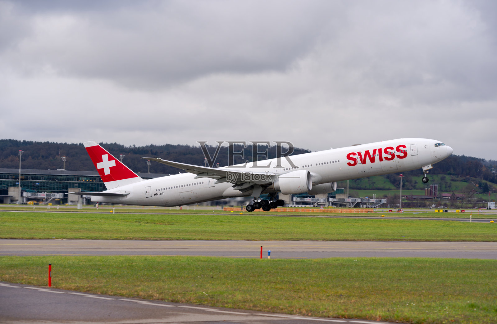 瑞士航空波音777-300ER客机HB-JNE在多云的秋日下午从苏黎世机场起飞的侧面视图。照片摄影图片